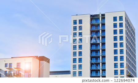 Modern apartment buildings on a sunny day with a blue sky. Facade of a modern apartment building. Glass surface with sunlight. 122694074