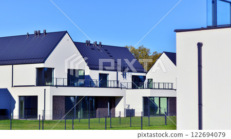 Terraced family homes in newly developed housing estate. The real estate market in the suburbs. New single family houses in a new development area. Residential homes with modern facade.  122694079