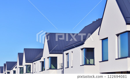Terraced family homes in newly developed housing estate. The real estate market in the suburbs. New single family houses in a new development area. Residential homes with modern facade.  122694081