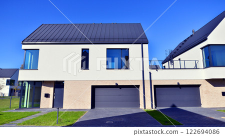 Terraced family homes in newly developed housing estate. The real estate market in the suburbs. New single family houses in a new development area. Residential homes with modern facade.  122694086
