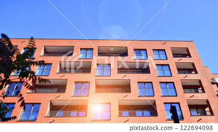 Modern apartment buildings on a sunny day with a blue sky. Facade of a modern apartment building. Glass surface with sunlight. Modern apartment buildings on a sunny day with a blue sky. Facade of a modern apartment building. Glass surface with sunlight. 122694098