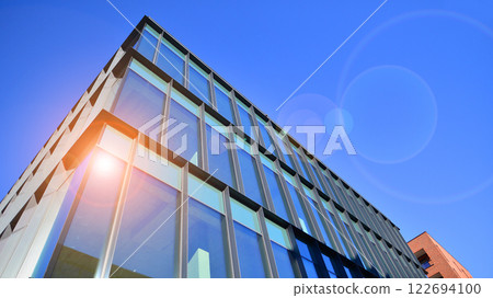 Glass building with transparent facade of the building and blue sky. Structural glass wall reflecting blue sky. Abstract modern architecture fragment. Contemporary architectural background. Glass building with transparent facade of the building and blue sky. Structural glass wall reflecting blue sky. Abstract modern architecture fragment. Contemporary architectural background. 122694100
