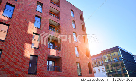 Modern apartment buildings on a sunny day with a blue sky. Facade of a modern apartment building. Glass surface with sunlight. Modern apartment buildings on a sunny day with a blue sky. Facade of a modern apartment building. Glass surface with sunlight. 122694106