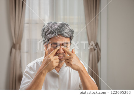 Senior man eye strain after for long stretches at computer or digital screens. Senior man eye strain after for long stretches at computer or digital screens. 122695293