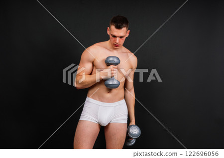 Muscular young man in white underwear with dumbbell in studio background 122696056