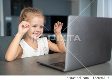 Little girl does finger gymnastics online on the laptop home. Distance learning concept. 122696193