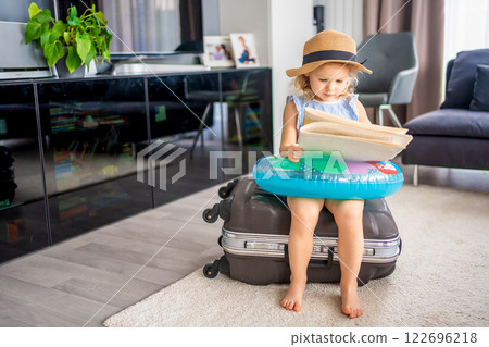 Little girl with suitcase baggage luggage and inflatable life buoy reading map and ready to go for traveling on vacation 122696218