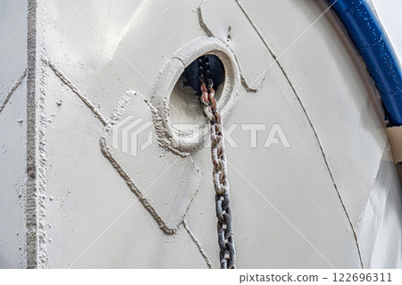 Ship's bow with anchor chains extending from the hawse holes, featuring weathered metal and welded seams detailed close view 122696311