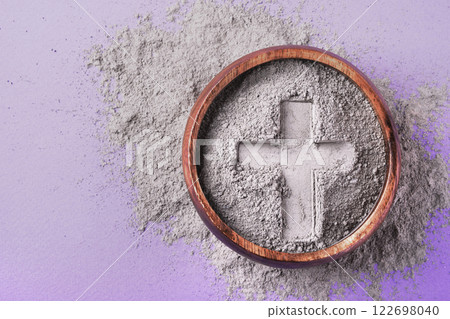 Cross imprint in gray ash on purple background. Ash Wednesday 122698040
