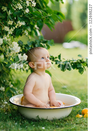 Child Playing In Outdoor Bath Tub Surrounded By Flowers 122698227