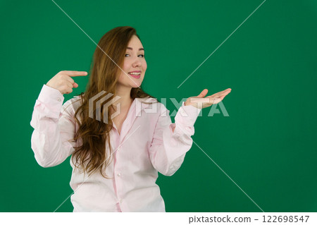Happy young woman pointing at something on green background 122698547