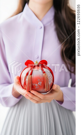 Asian female holding elegant red and white gift with bow and tassels Asian female holding elegant red and white gift with bow and tassels 122698686