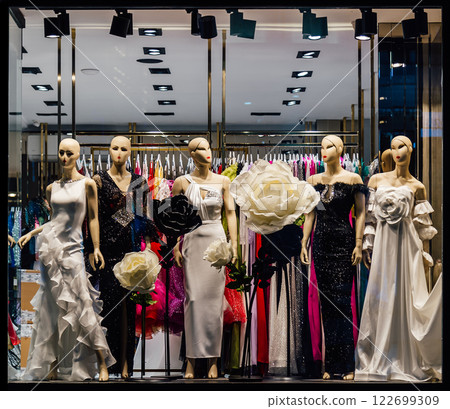 Elegant evening gowns displayed in a chic boutique window. Mannequins showcase luxurious fabrics and designs, perfect for fashion, retail, and luxury branding 122699309