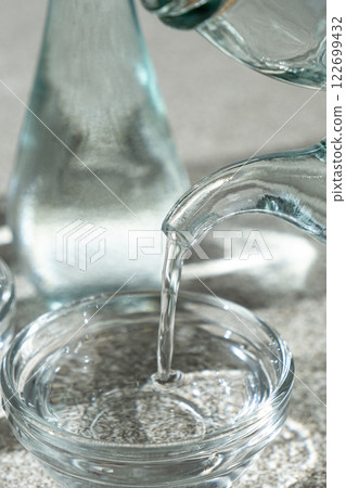 White distilled vinegar is poured into a glass vinegar bowl. White distilled vinegar is poured into a glass vinegar bowl. 122699432