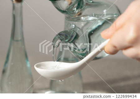 White distilled vinegar is poured into spoon 122699434