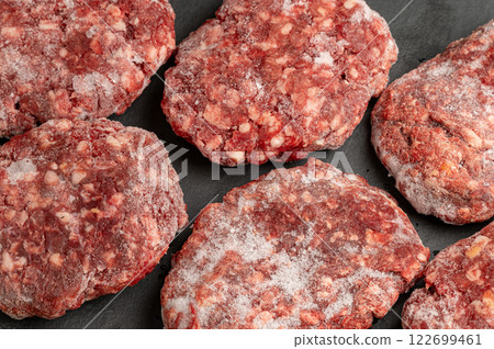 Close-up of several frozen hamburger patties on a dark surface. Ready for grilling or cooking. Perfect for recipe blogs and food websites 122699461