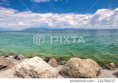 Lake Garda with mountains in background, view from shore in Sirmione town, Italy, Europe. 122700217