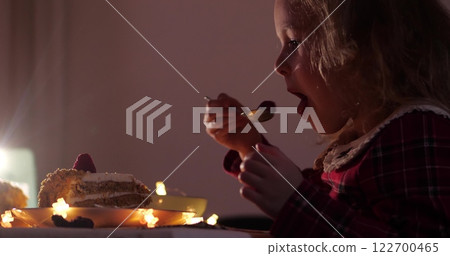 A little girl eats the Christmas raspberry cake in the evening 122700465