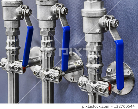 Valves and fittings installed on a wall in a mechanical workshop demonstrating industrial infrastructure 122700544