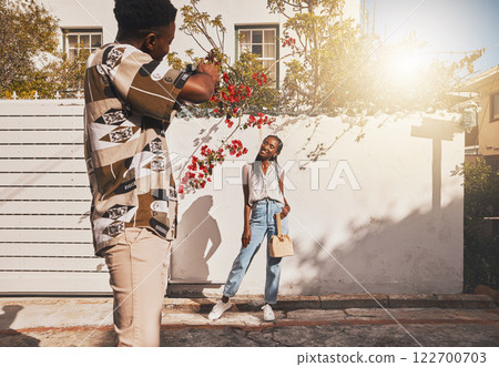 Photographer with model for summer fashion photography taking photo, posing and smiling for portrait shot with lens flare. African creative freelancer taking picture of young influencer woman outside Photographer with model for summer fashion photography taking photo, posing and smiling for portrait shot with lens flare. African creative freelancer taking picture of young influencer woman outside 122700703