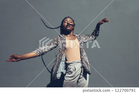 Fashion, style and trendy black woman against a gray background wall in a city, town and downtown. Street beauty model with funky, cool and hipster hair in edgy motion or movement expression outdoors Fashion, style and trendy black woman against a gray background wall in a city, town and downtown. Street beauty model with funky, cool and hipster hair in edgy motion or movement expression outdoors 122700791