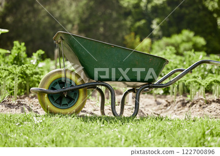 Farm or garden wheelbarrow on nature, agriculture environment or green countryside field used for farming work. Gardening equipment for lawn with sustainable grass, flower and plant growth 122700896
