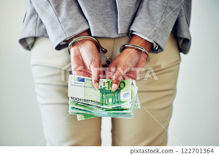 Corporate fraud, stealing or money laundering deal of a business woman with handcuffs and cash. Back hands view of legal justice of a caught white collar work employee going to court, jail or prison Corporate fraud, stealing or money laundering deal of a business woman with handcuffs and cash. Back hands view of legal justice of a caught white collar work employee going to court, jail or prison 122701364