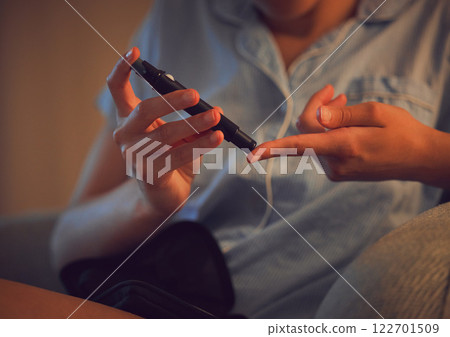 Diabetic, Diabetes or chronic disease by a woman testing blood sugar or glucose levels at home using a lancet pen. Closeup of a female piercing her finger to control her health condition 122701509