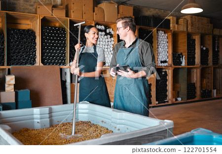 Winemaker partners crush grapes while researching the fermentation process on a digital tablet at winery. Young colleagues bonding and enjoying job, discussing the blend and flavor of last harvest 122701554