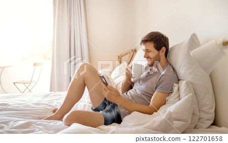 Relax man in bed, using phone and happy while drinking coffee in the morning reading emails, using internet or social media. Person using smartphone for 5g communication or conversation in a bedroom Relax man in bed, using phone and happy while drinking coffee in the morning reading emails, using internet or social media. Person using smartphone for 5g communication or conversation in a bedroom 122701658