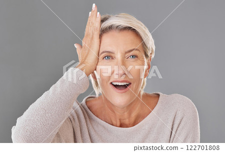 Thinking, idea or memory with a senior woman knocking her head with her hand to remember or forget in studio on a grey background. Face portrait of a model with grey hair having a light bulb moment 122701808