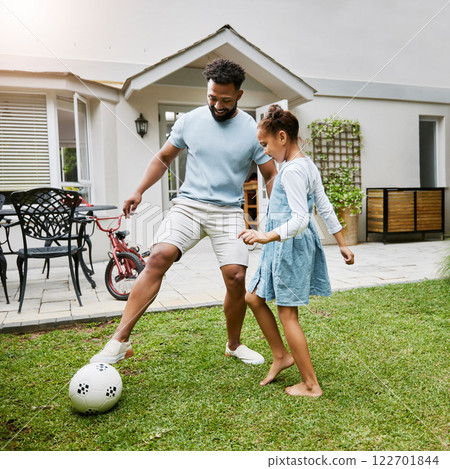 Father and daughter bonding, playing with soccer ball in backyard at home, smiling and having fun. Happy parent being playful and enjoying family time with his child. Guy being active with his kid 122701844