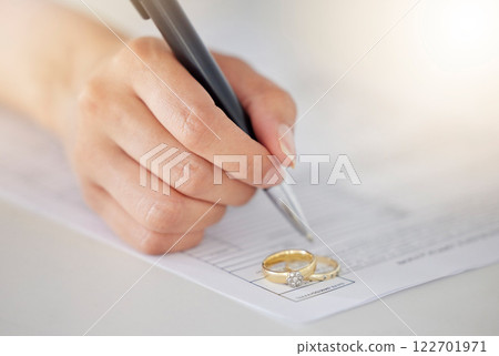 Woman hand signing legal divorce documents, deal or paper contract in a lawyer office with ring placed on table. Person writing signature on marriage paperwork after agreement at family law office Woman hand signing legal divorce documents, deal or paper contract in a lawyer office with ring placed on table. Person writing signature on marriage paperwork after agreement at family law office 122701971