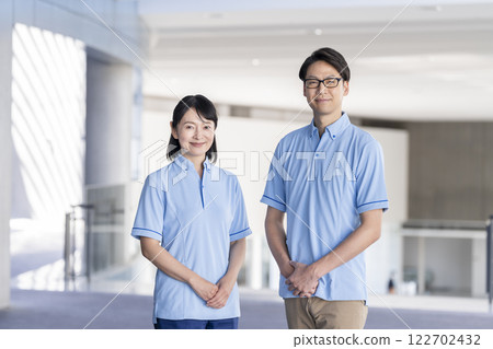 Image of a middle-aged man and woman looking at the camera wearing a blue polo shirt, facility staff 122702432