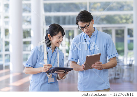 Facility staff holding a meeting while looking at a tablet Facility staff holding a meeting while looking at a tablet 122702611