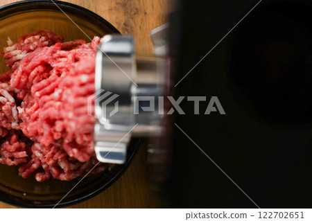 The concept of healthy and proper nutrition, cooking. Top and left view of red ground beef with streaks of fat coming out of a metal grinder with space for text on the right on a black background 122702651