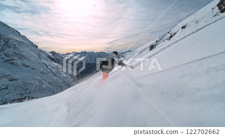 Snowboard rider riding down fresh powder during sunny day , Alpine scenery 122702662