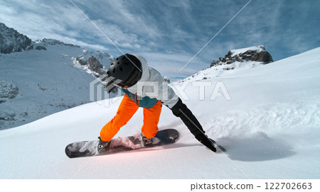Snowboard rider riding down fresh powder during sunny day , Alpine scenery 122702663