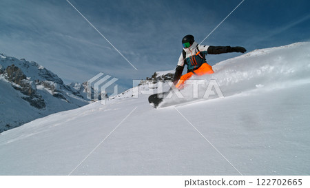 Snowboard rider riding down fresh powder during sunny day , Alpine scenery 122702665
