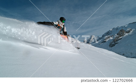 Snowboard rider riding down fresh powder during sunny day , Alpine scenery 122702666