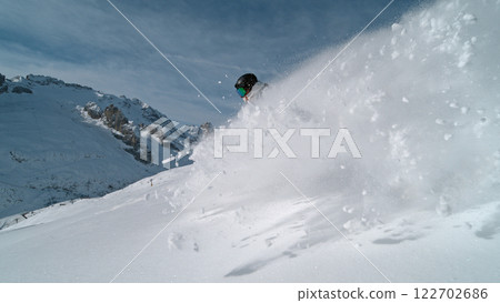 Snowboard rider riding down fresh powder during sunny day , Alpine scenery 122702686