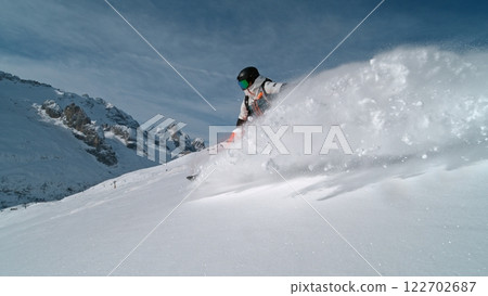 Snowboard rider riding down fresh powder during sunny day , Alpine scenery 122702687