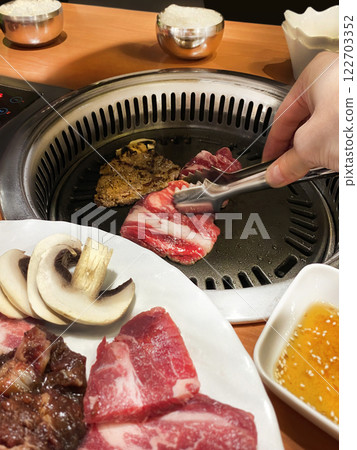 Korean barbecue, roasting marbled beef, champignons over a fire in the middle of the table. Korean snacks. Vertical Korean barbecue, roasting marbled beef, champignons over a fire in the middle of the table. Korean snacks. Vertical 122703352