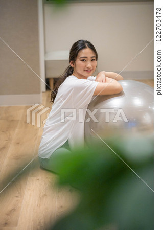 Young woman exercising with a balance ball 122703478