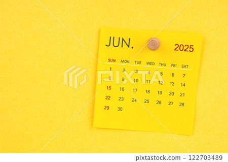 June 2025 calendar sheet with thumbtack on yellow background. 122703489