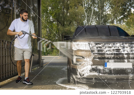 man washing a car in a self-service car wash station with wahing foam. Wash car self-service station man washing a car in a self-service car wash station with wahing foam. Wash car self-service station 122703918