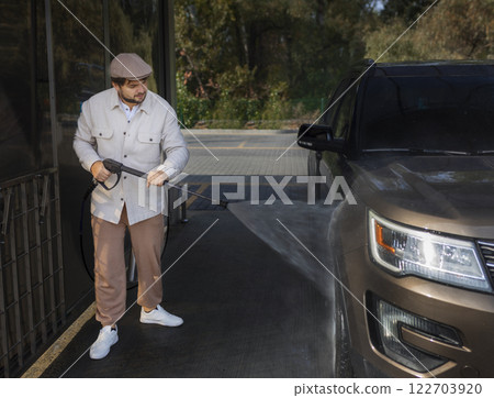 man washing a car in a self-service car wash station with wahing foam. Wash car self-service station 122703920