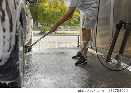 the man herself at the car wash washes the car with a brush the man herself at the car wash washes the car with a brush 122703924