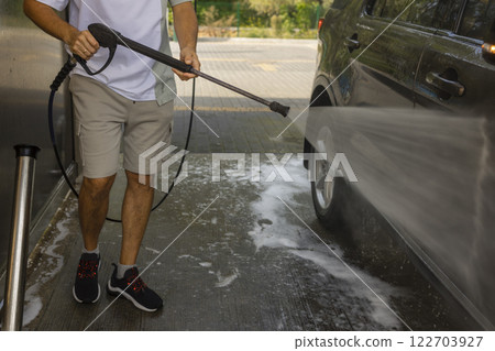 man washing a car in a self-service car wash station with wahing foam. Wash car self-service station 122703927