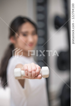 Young woman training with dumbbells 122704180